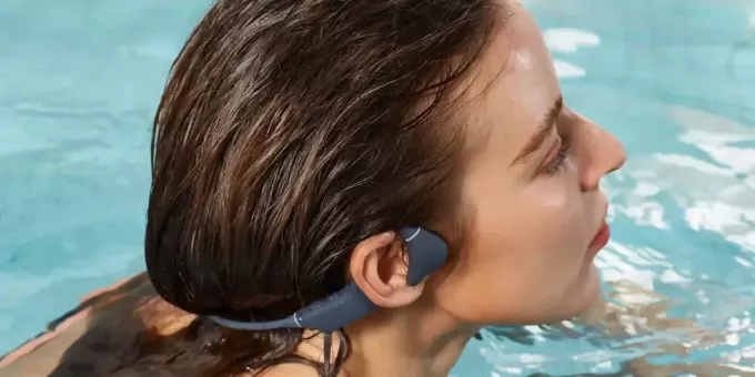 Kvinne svømmer med beinledningshodetelefoner